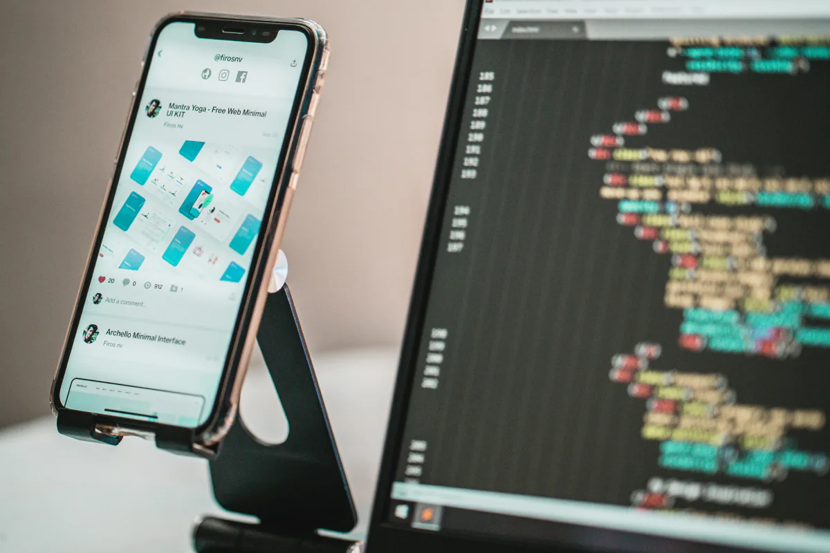 A mobile application beside a computer screen displaying code