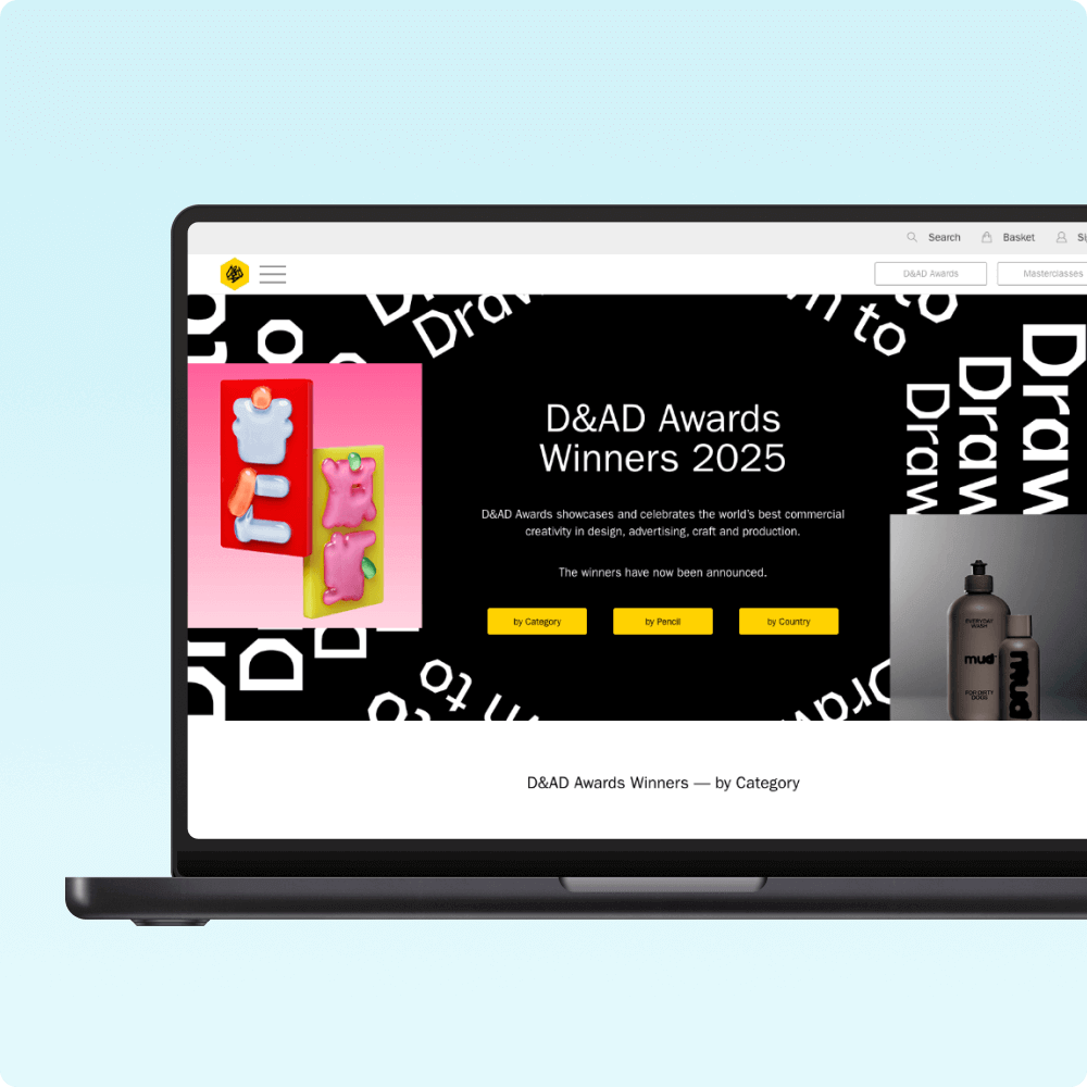 A laptop displaying the D&AD Awards Winners 2025 page, featuring colorful awards on a black background, emphasizing creativity and design excellence. The layout includes categories and a call-to-action for exploring the winning entries.