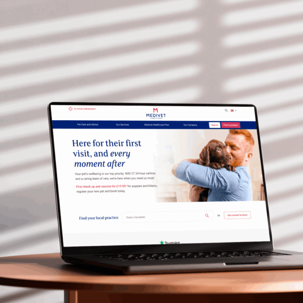 A laptop displaying a veterinary website, featuring a welcoming message about first visits and a caring interaction between a man and a dog. The design emphasizes warmth and trust in pet care.