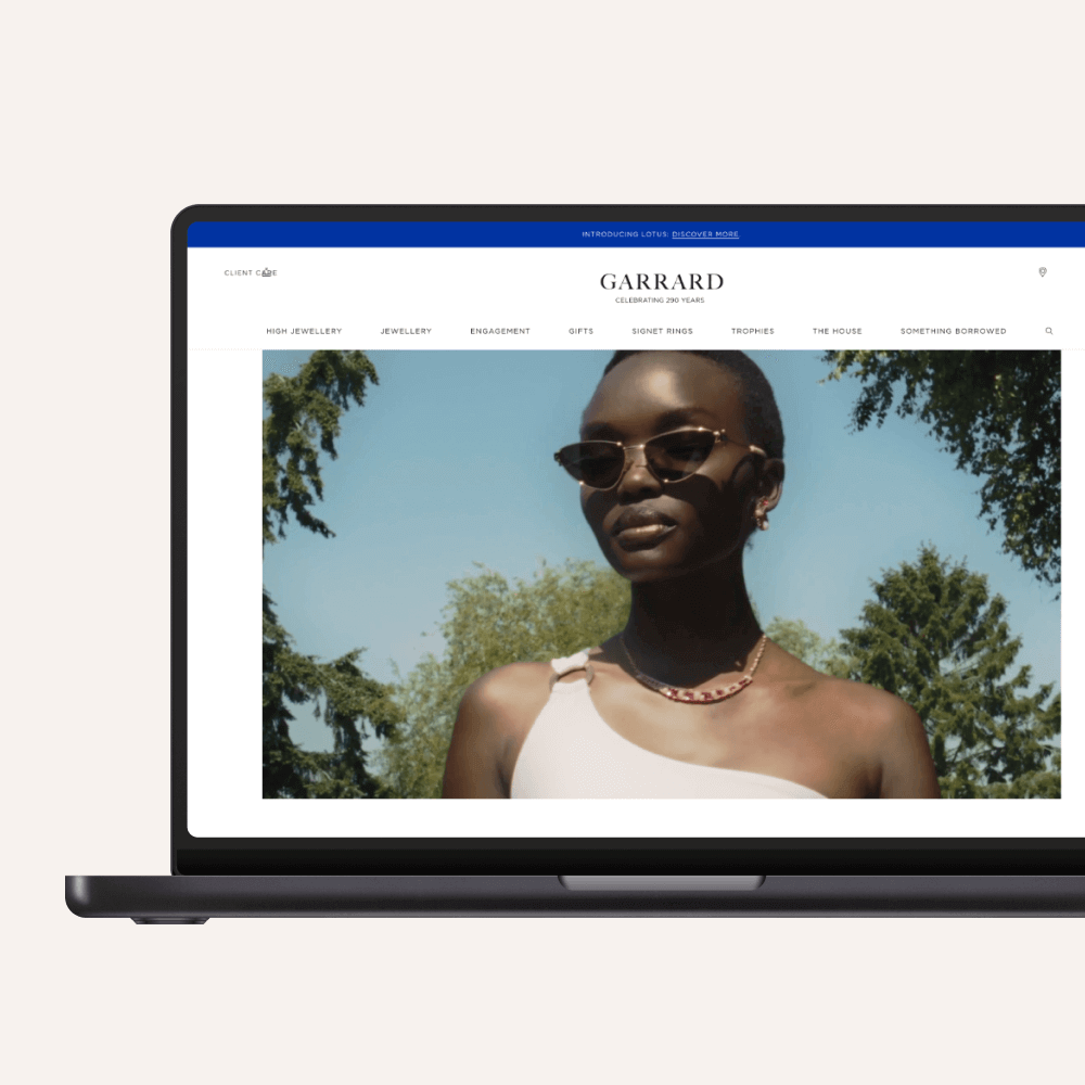 A laptop displays a fashion website featuring a model wearing sunglasses, highlighting a stylish summer look against a backdrop of trees. The site emphasizes modern aesthetics and elegance.