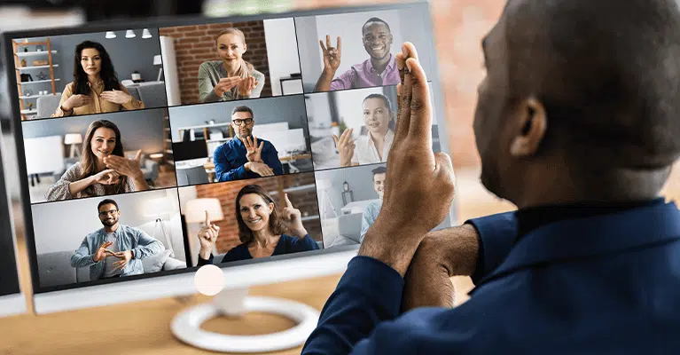 Picture shows a man signing to other people who are signing back, during a video call on a laptop