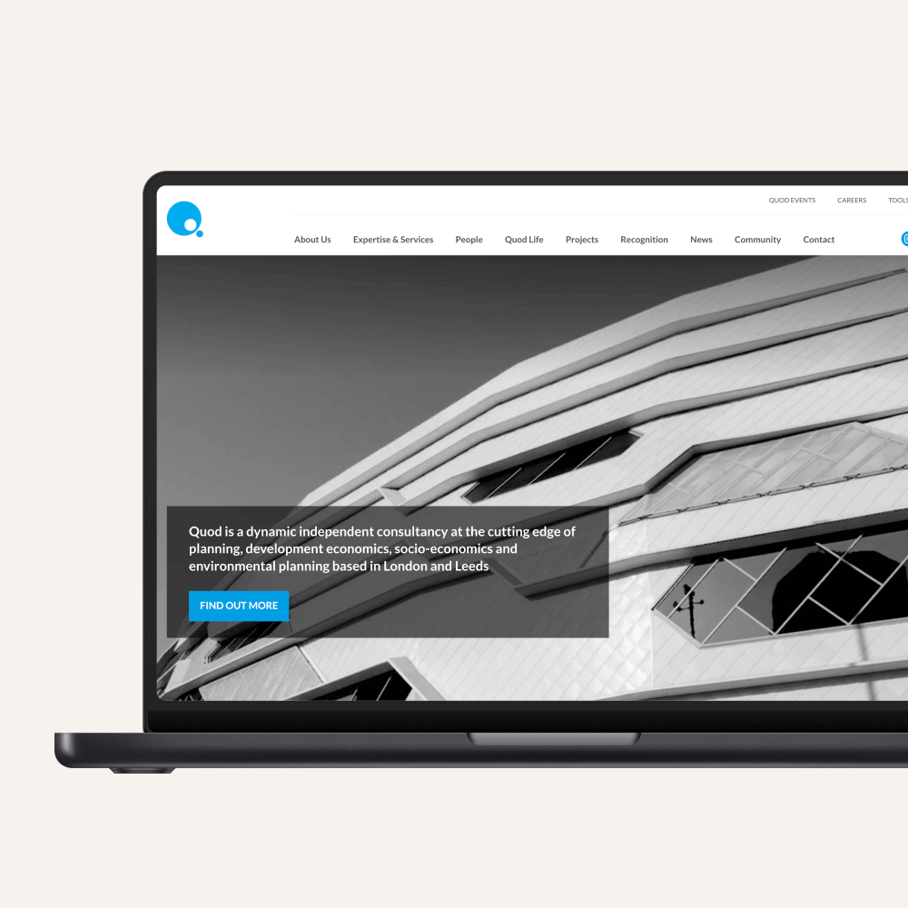 A laptop displays the homepage of Quid, an independent consultancy focused on planning, development economics, and environmental planning. The design emphasizes modern architecture with a sleek, geometric building graphic.
