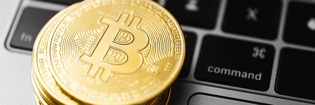 Gold coins featuring the Bitcoin logo, stacked ontop of a laptop keyboard.
