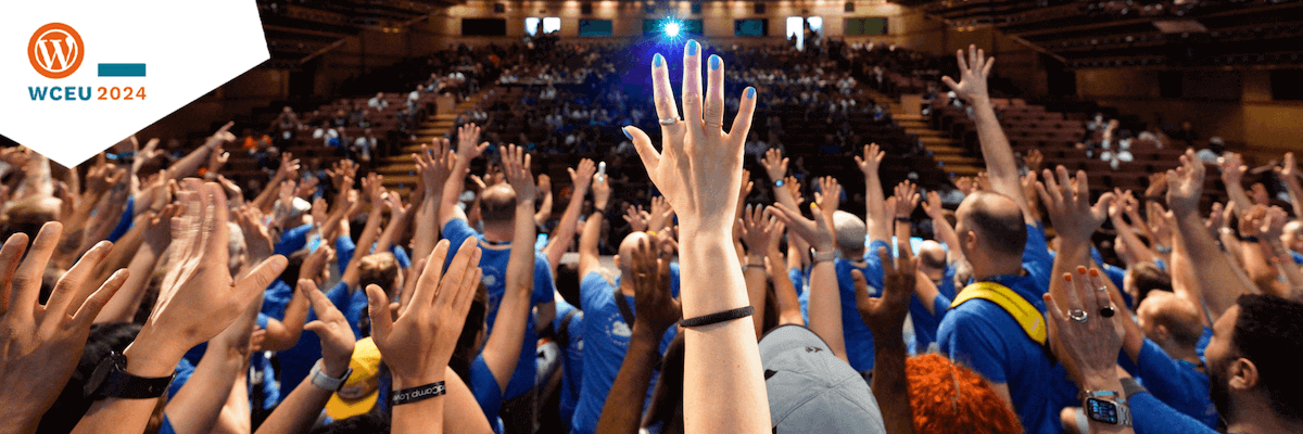 A crowd of people in blue shirts enthusiastically raise their hands inside a large auditorium. The venue is filled with attendees, and a bright light shines from the stage area. The top left corner displays the WCEU 2024 logo.