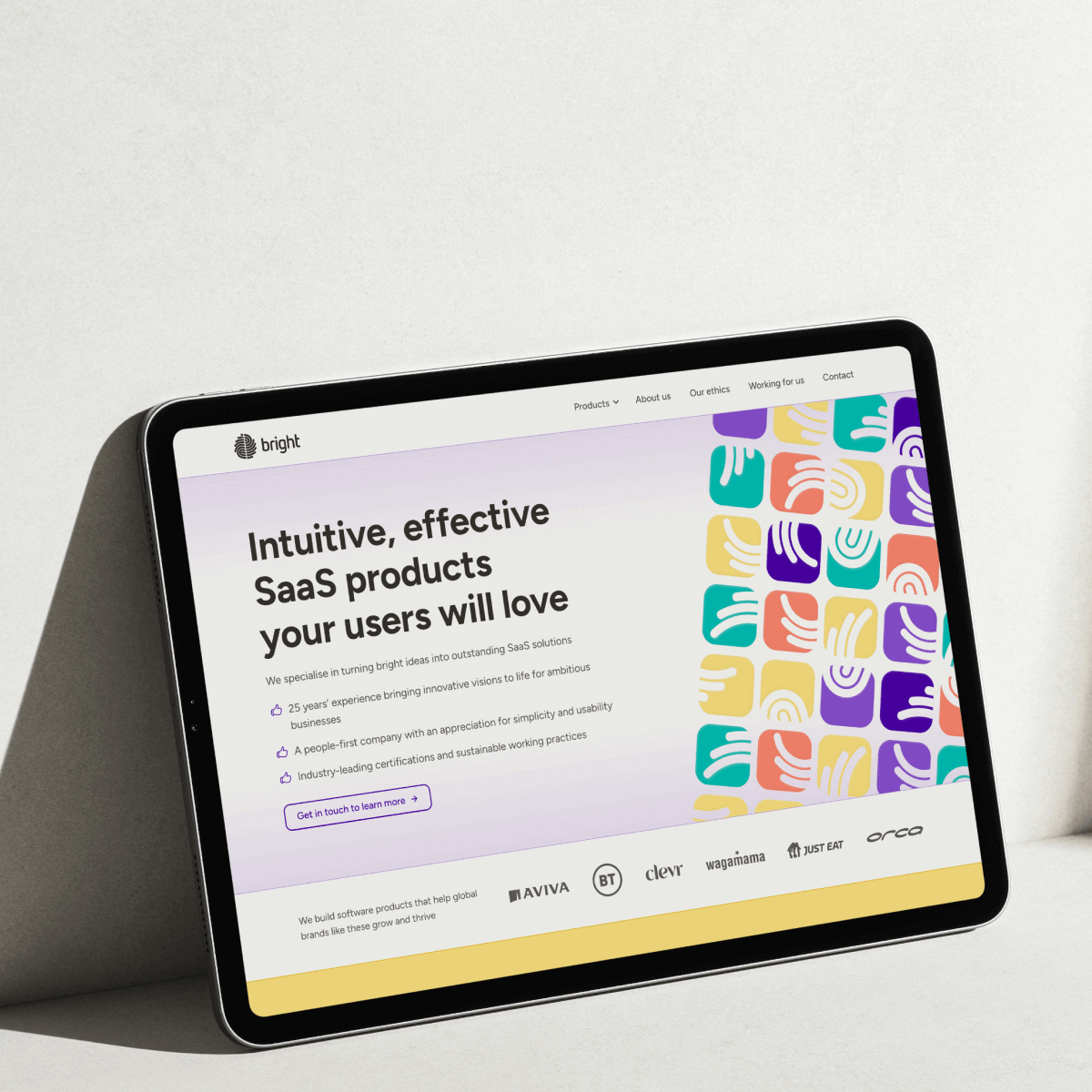 Tablet displaying a webpage with the text "Intuitive, effective SaaS products your users will love" next to colorful abstract hand motifs and logos of various partner companies below.