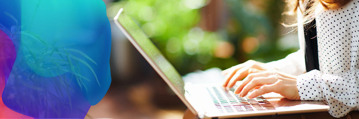 A person wearing a white polka dot shirt types on a laptop, seated outdoors. The image has a vibrant, colorful overlay on the left side, adding an abstract visual effect.