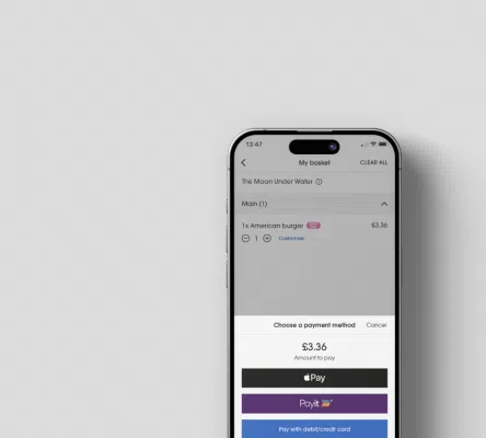 A smartphone screen displays a food order from "The Moon Under Water," featuring an American burger costing £3.36. Payment options include Apple Pay, PayIt, and paying with a debit or credit card, all shown against a minimalist grey background.