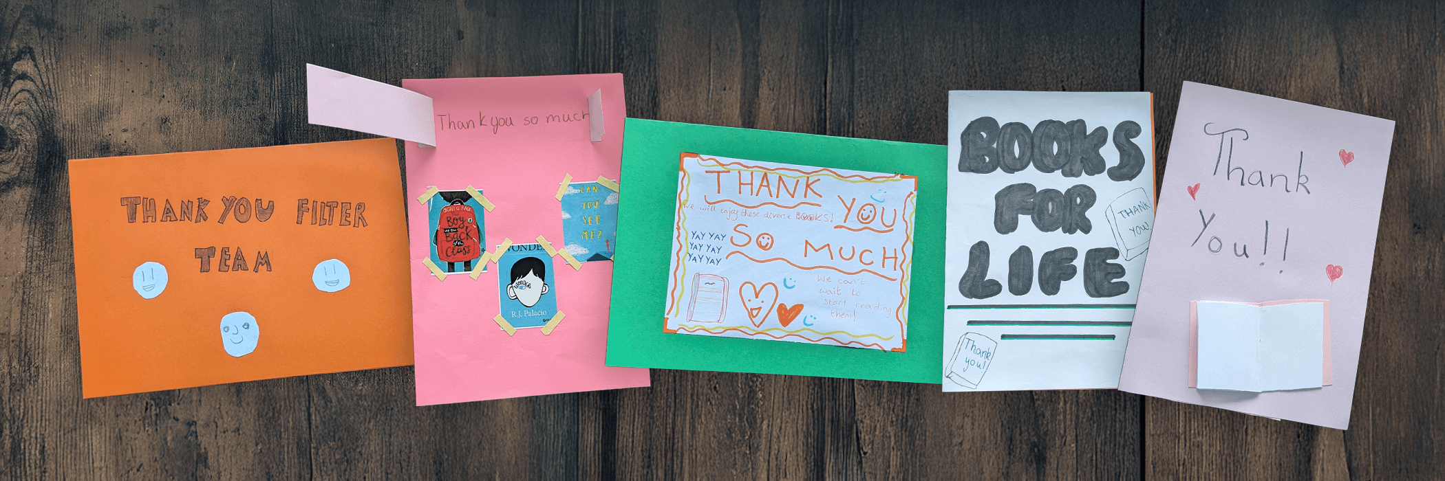 Five handmade thank-you cards with colorful designs and messages lie on a wooden surface.