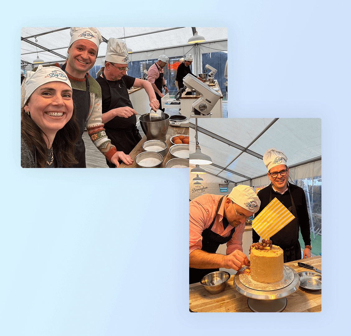 A group of smiling individuals in aprons and chef hats are engaged in baking activities inside a large tent. One person decorates a cake while others prepare ingredients.