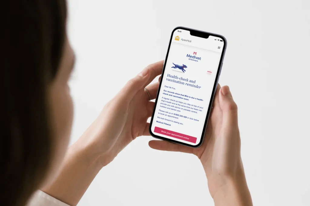 A woman holds a smartphone showing a Medivet email in the ApexMail app – a health-check and vaccination reminder for a dog named Milo, with a running dog illustration and a "Book your appointment online" button.
